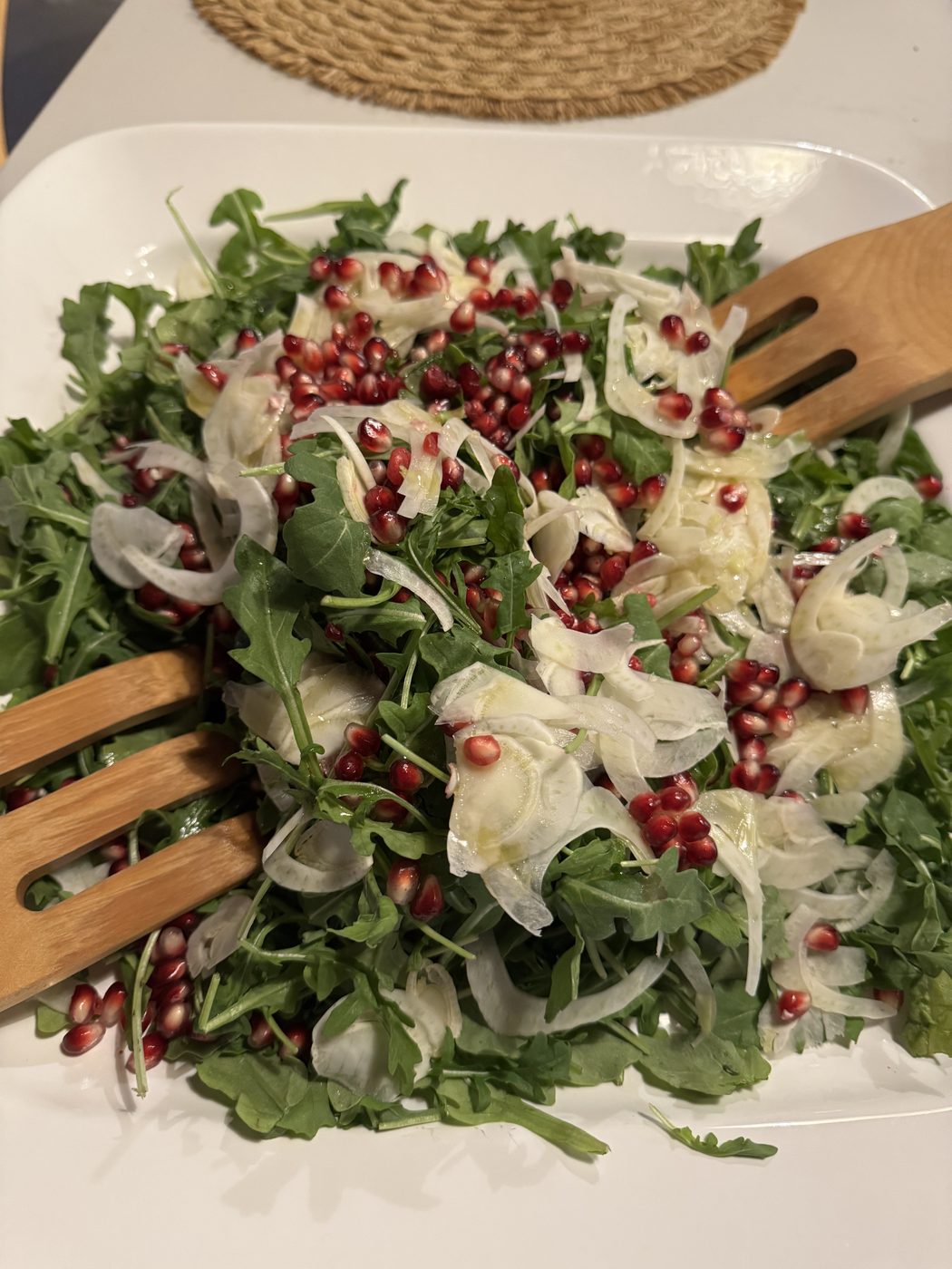 Arugula and shaved fennel salad scattered with pomegranate seeds.