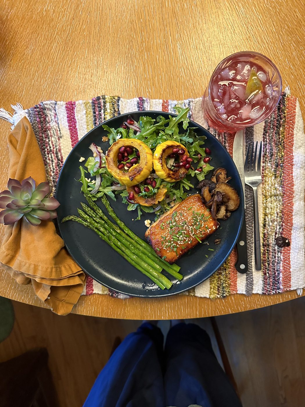 A plated dinner of salmon, asparagus and stuffed squash with a sparkling drink.