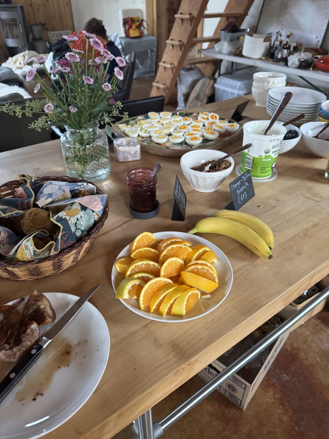 A breakfast spread with sliced oranges, bananas, deviled eggs and wildflowers.
