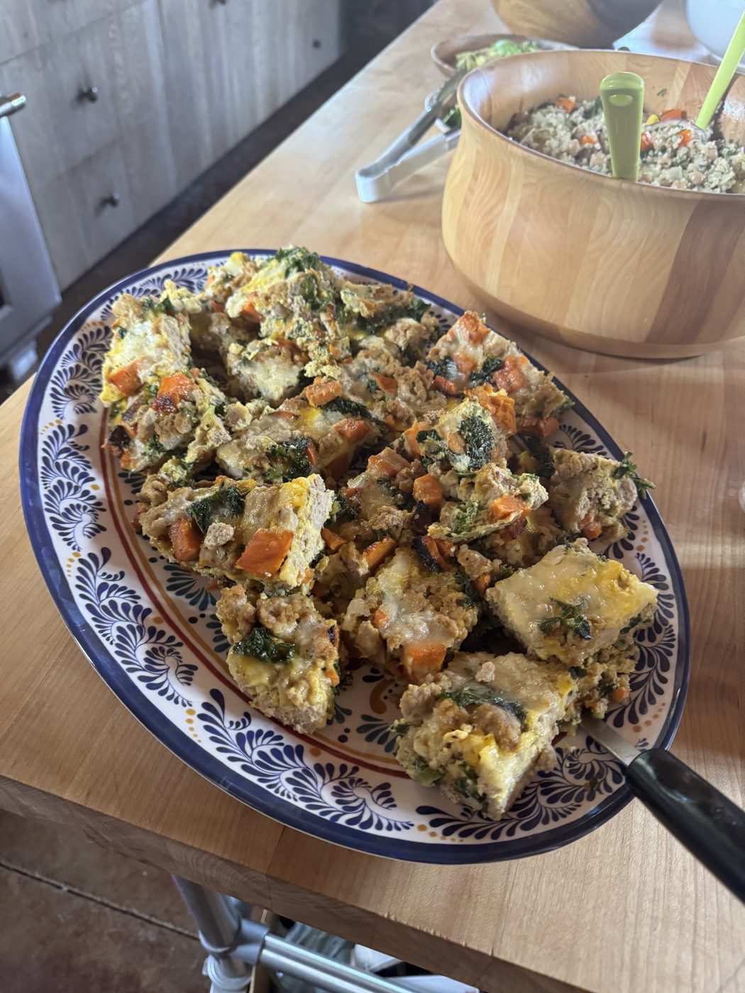 A platter of vegetable frittata squares beside a bowl of quinoa salad.