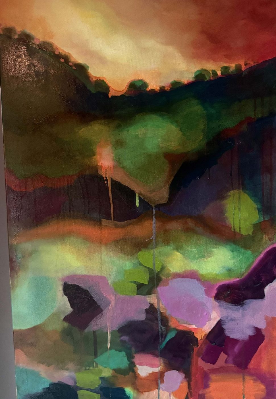 Abstract painting of glowing green, pink and violet forms under a warm orange sky, with paint drips running down the canvas.