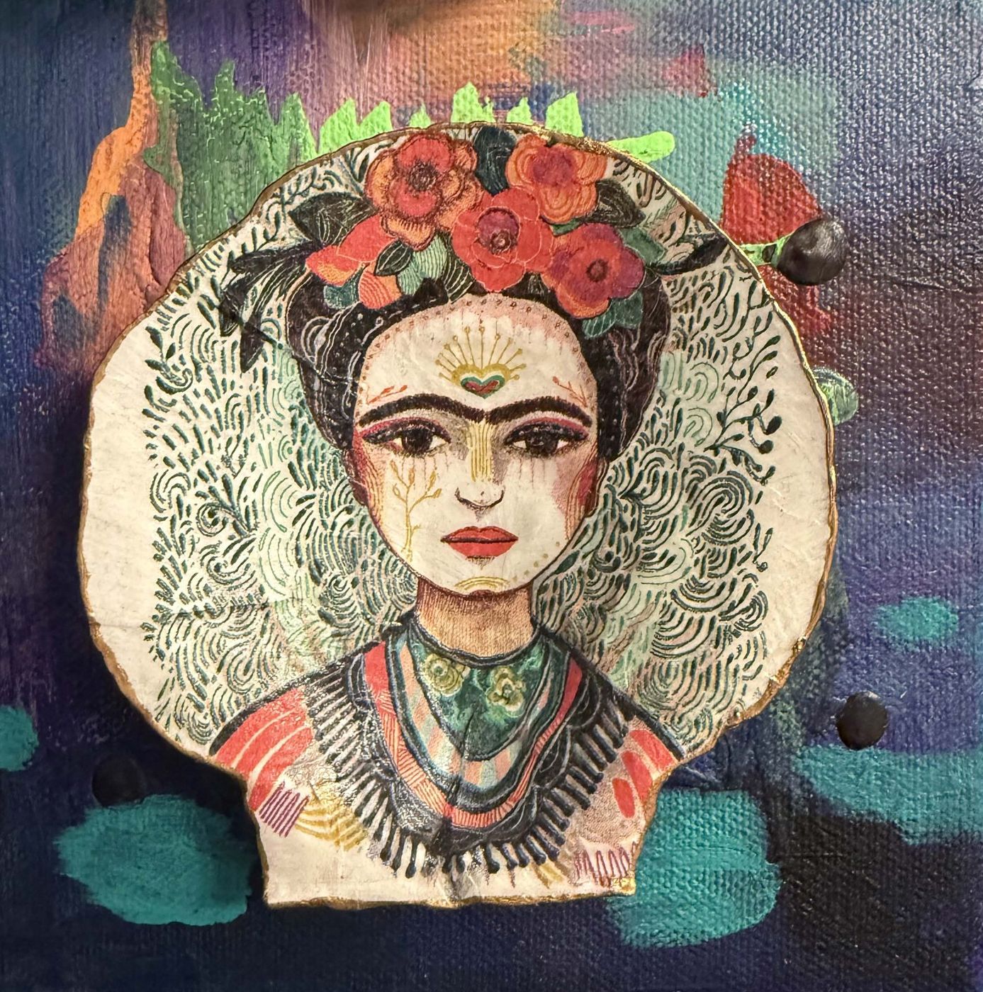 Mixed media portrait of Frida Kahlo with red flowers in her hair, on a patterned paper shape over a blue and teal canvas.