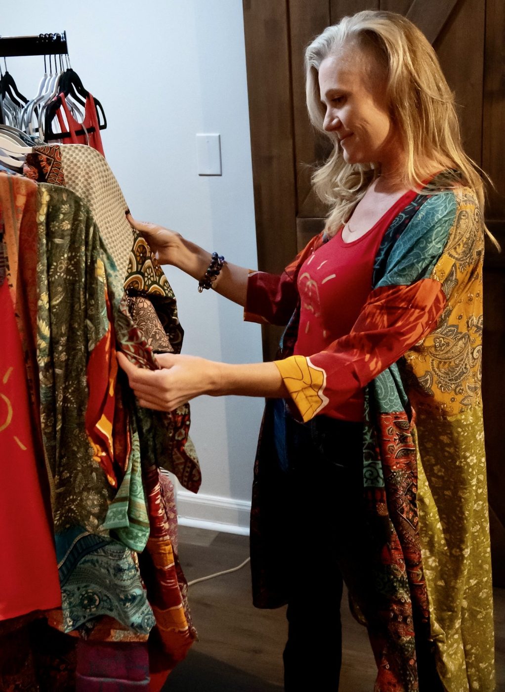 A woman looking through a rack of colorful patterned jackets.