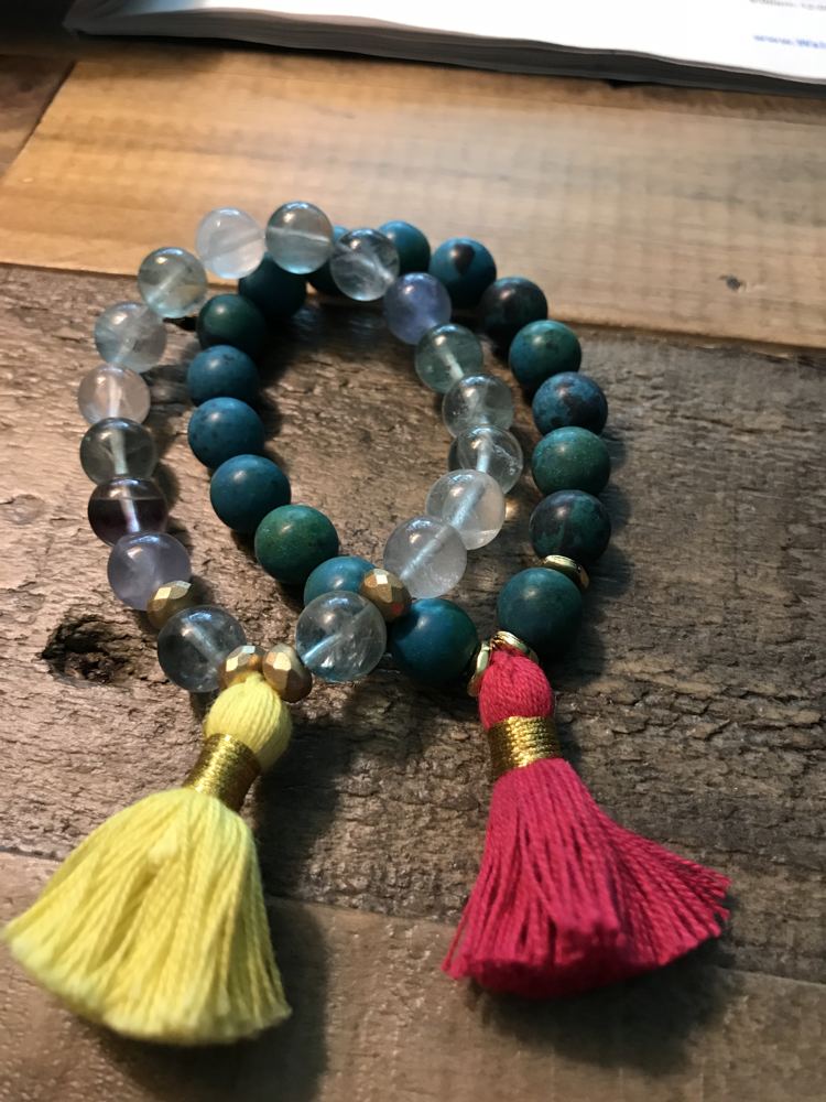 Two stone bead bracelets with yellow and red tassels.