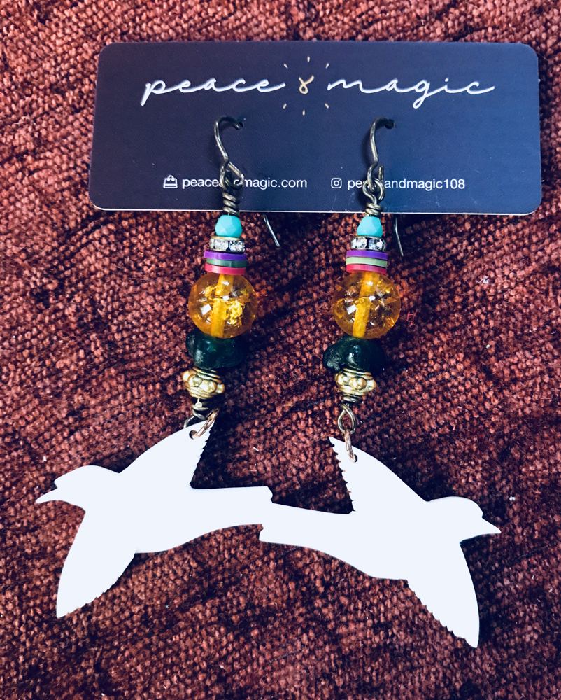 Beaded earrings with amber and blue glass, shown with white bird cutouts.