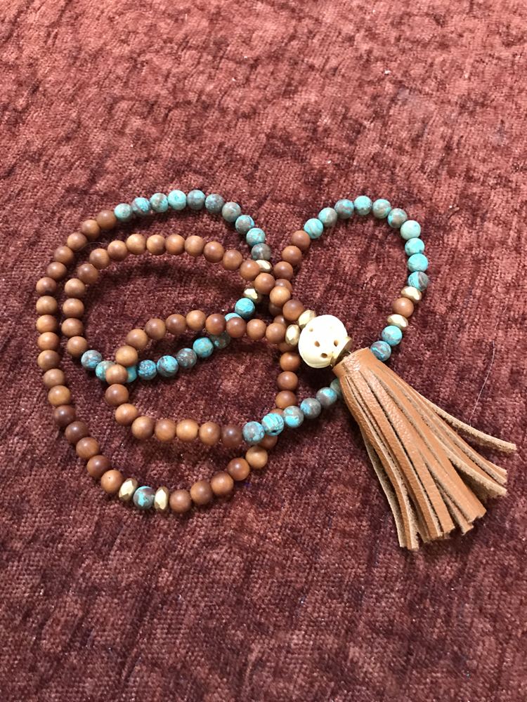 Wood and turquoise bead mala with a carved bead and a suede tassel.