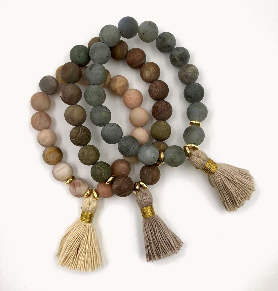 Three matte stone bracelets with natural tassels.