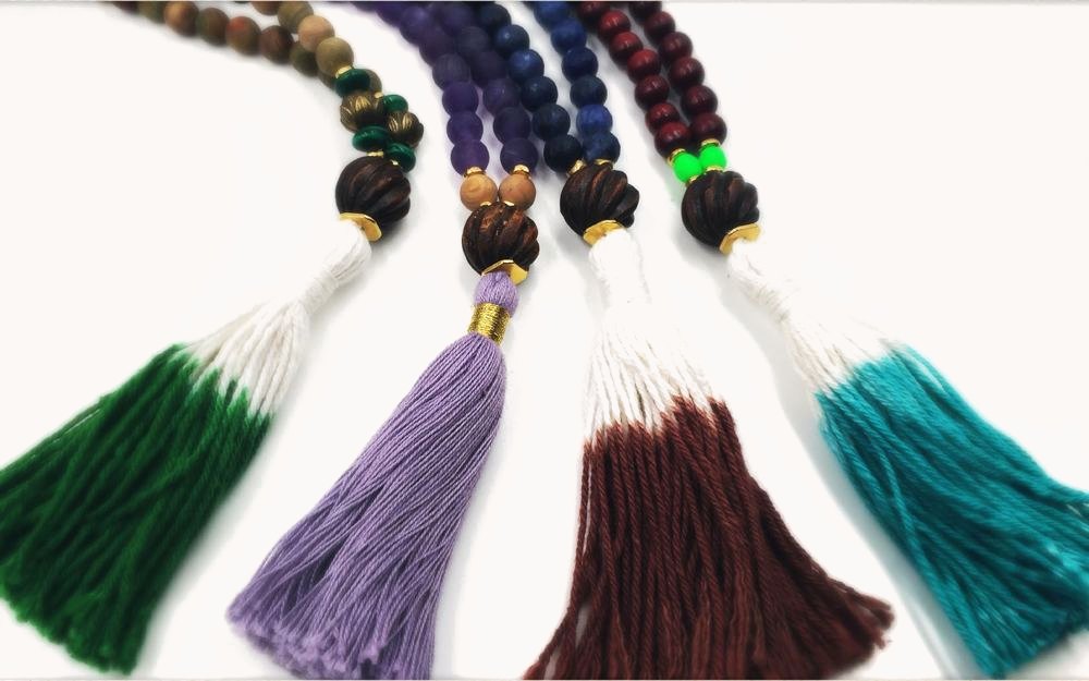 Four malas with ombre tassels in green, lavender, brown and teal.