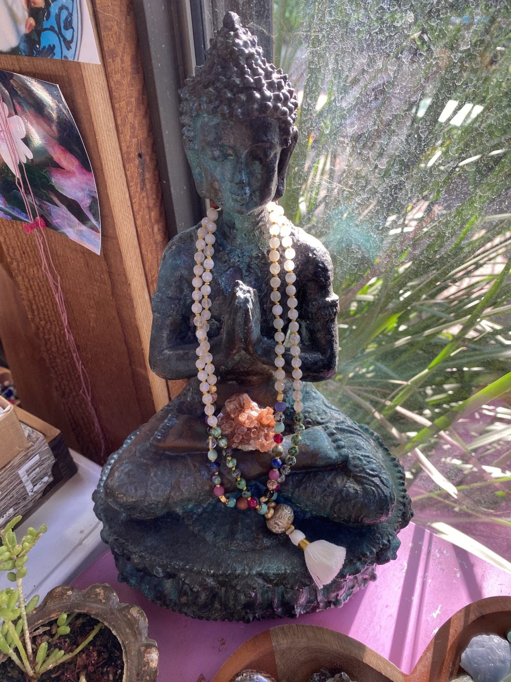 Layered gemstone malas draped on a seated Buddha statue.
