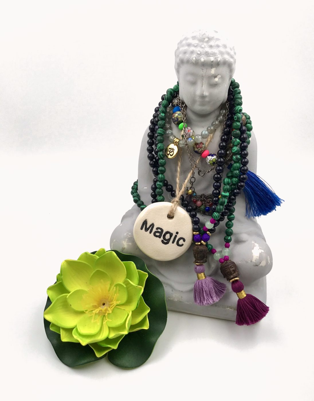 Green and purple malas on a white Buddha with a Magic charm and a green lotus.
