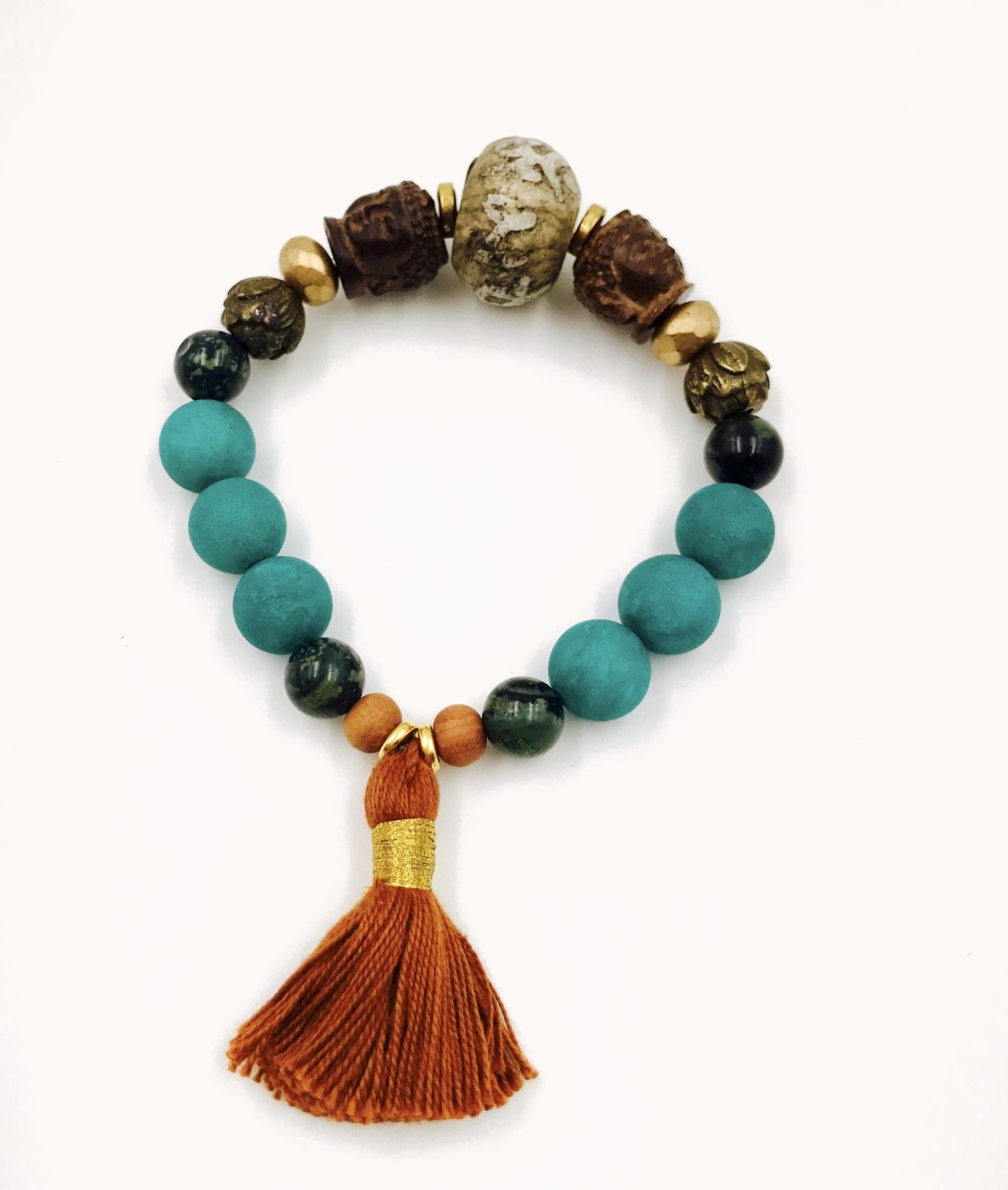 A turquoise bead bracelet with carved wooden beads and an orange tassel.