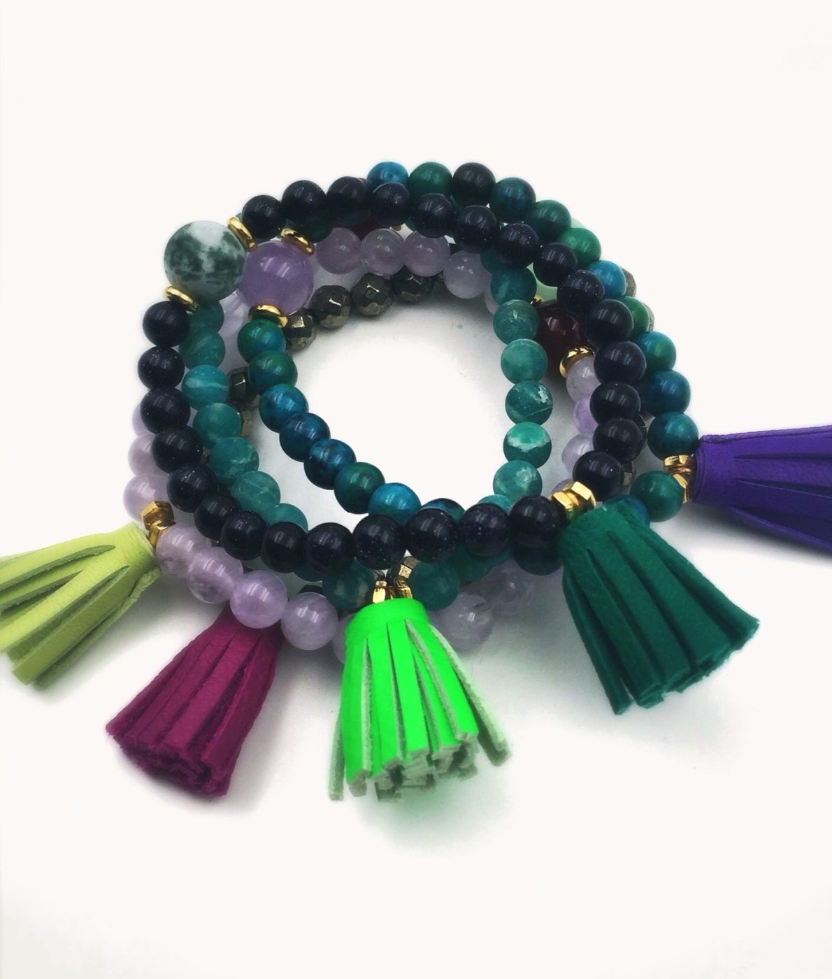 A stack of teal and amethyst bracelets with suede tassels.