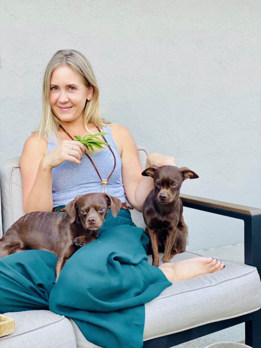 Amy relaxing on an outdoor sofa with her two small brown dogs.