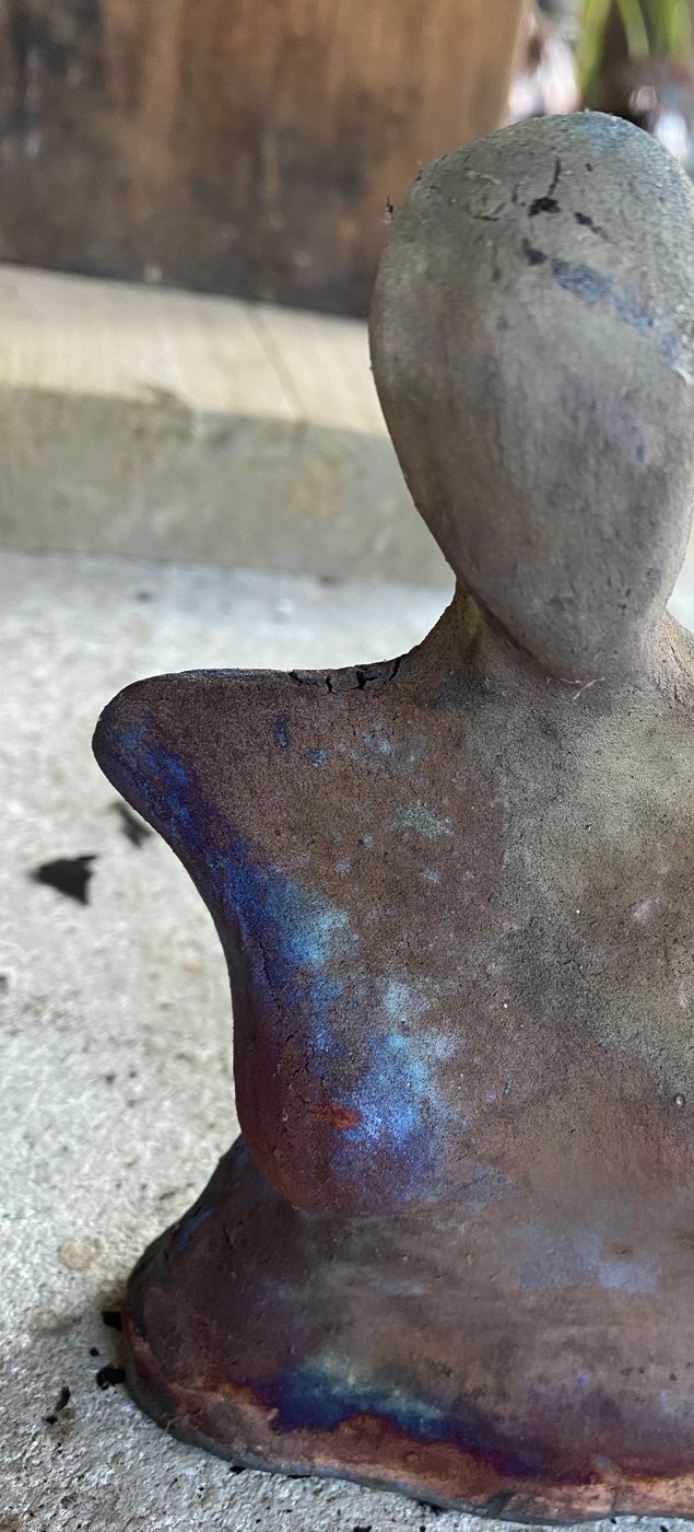 A matte raku goddess in smoky gray, with blue and violet flashing at her hips.