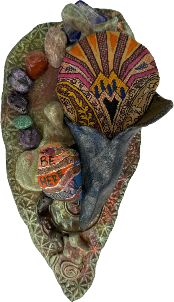 A raku leaf-shaped piece with tumbled stones, a calla lily form holding embroidered fabric, and a painted stone reading Be Here.