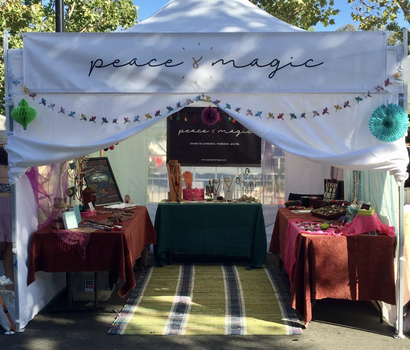 The Peace & Magic tent with its logo banner and garland.