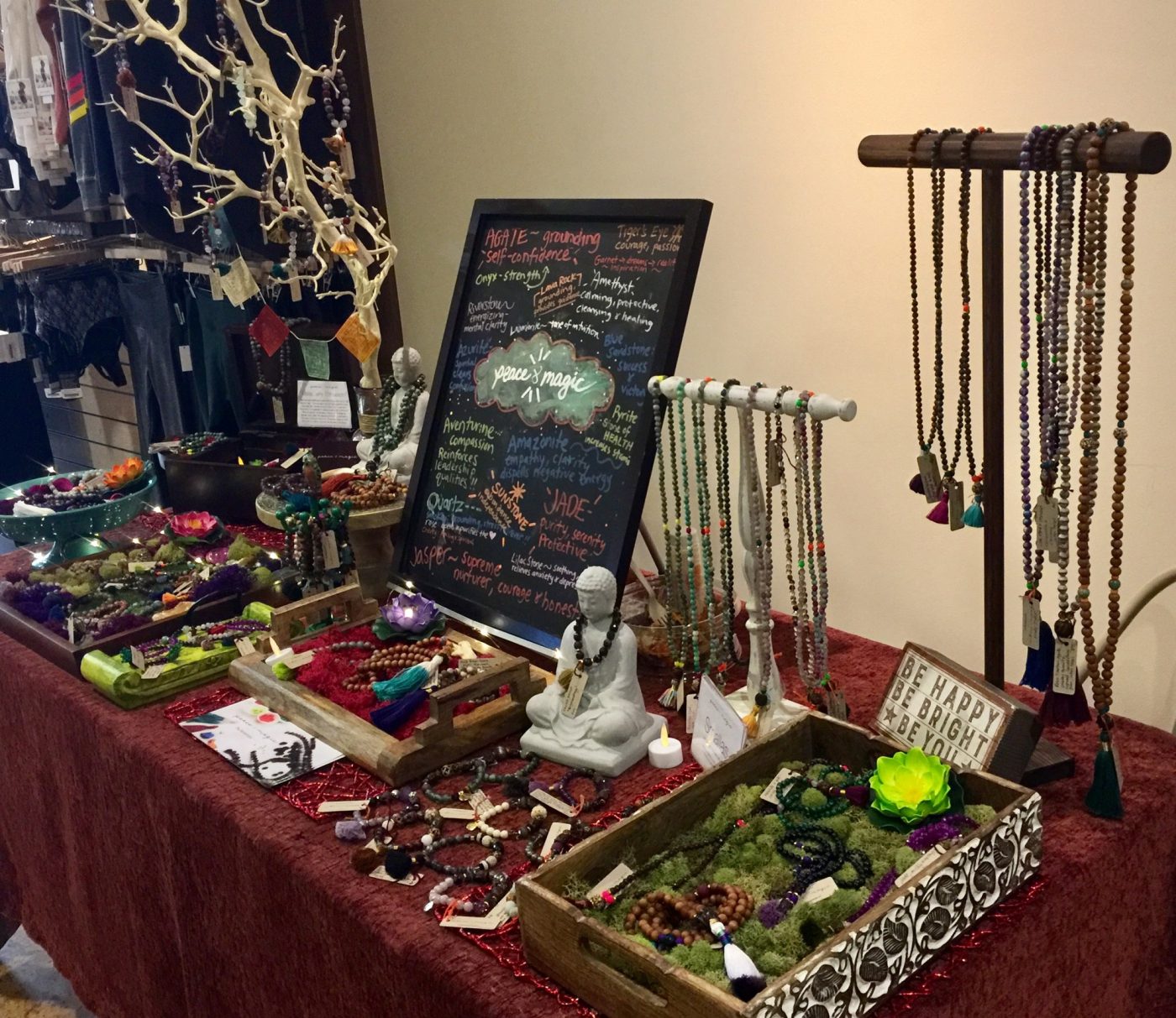 An indoor table of malas, bracelets and a chalkboard sign.