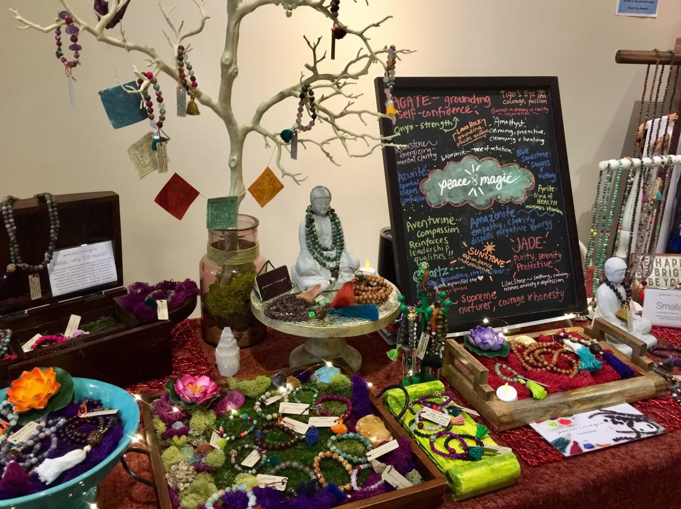 A jewelry table with a branch display, Buddha figure and moss.