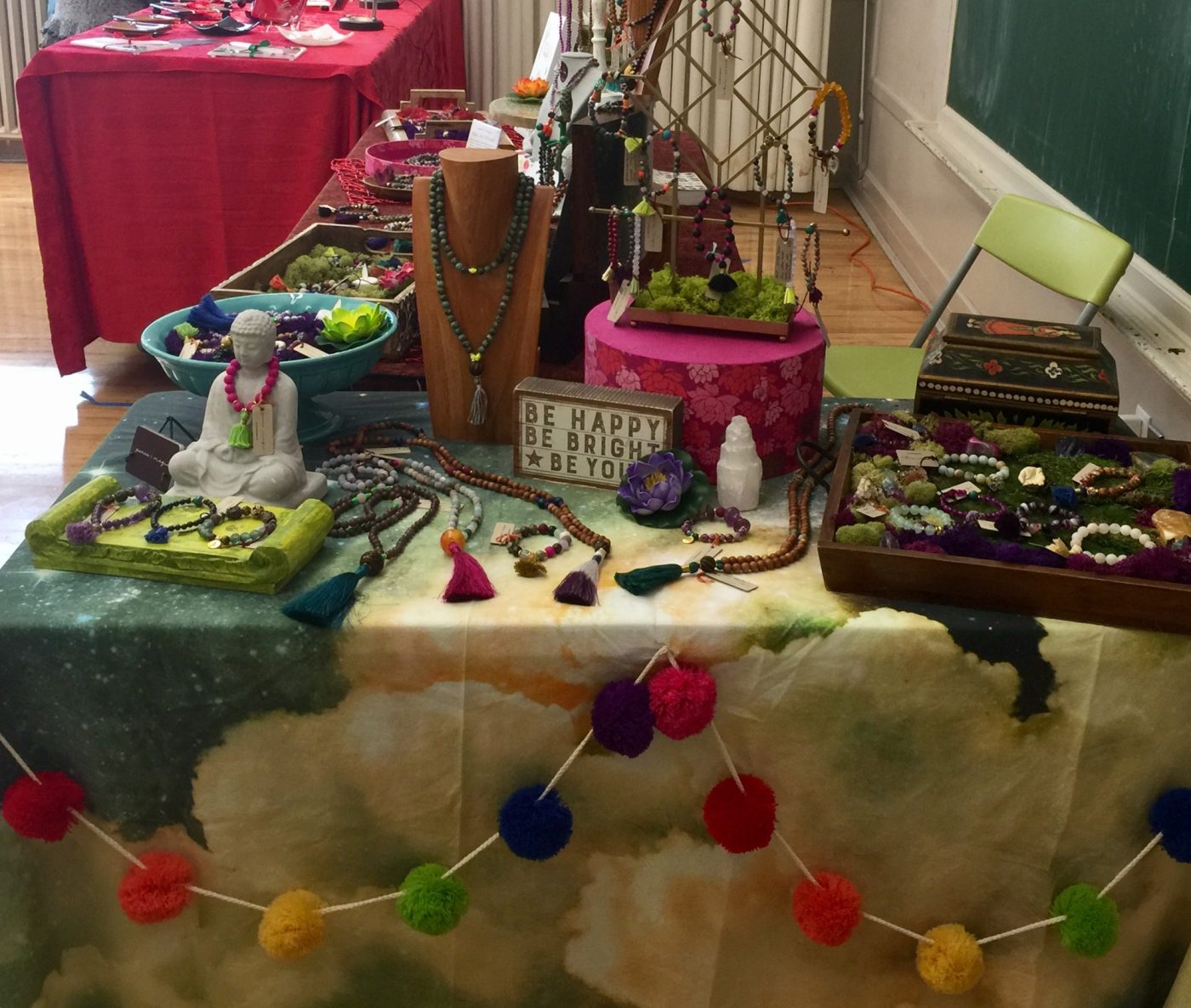 A pop up table with a pompom garland, Buddha and jewelry boxes.