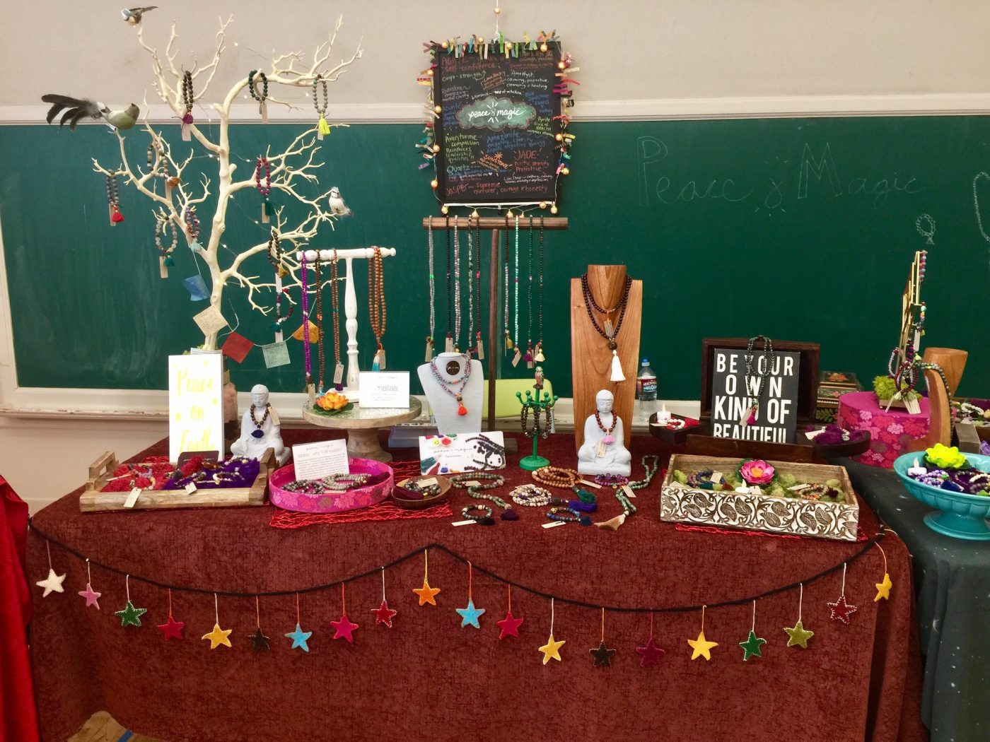 A schoolroom pop up with a star garland and a branch of hanging jewelry.