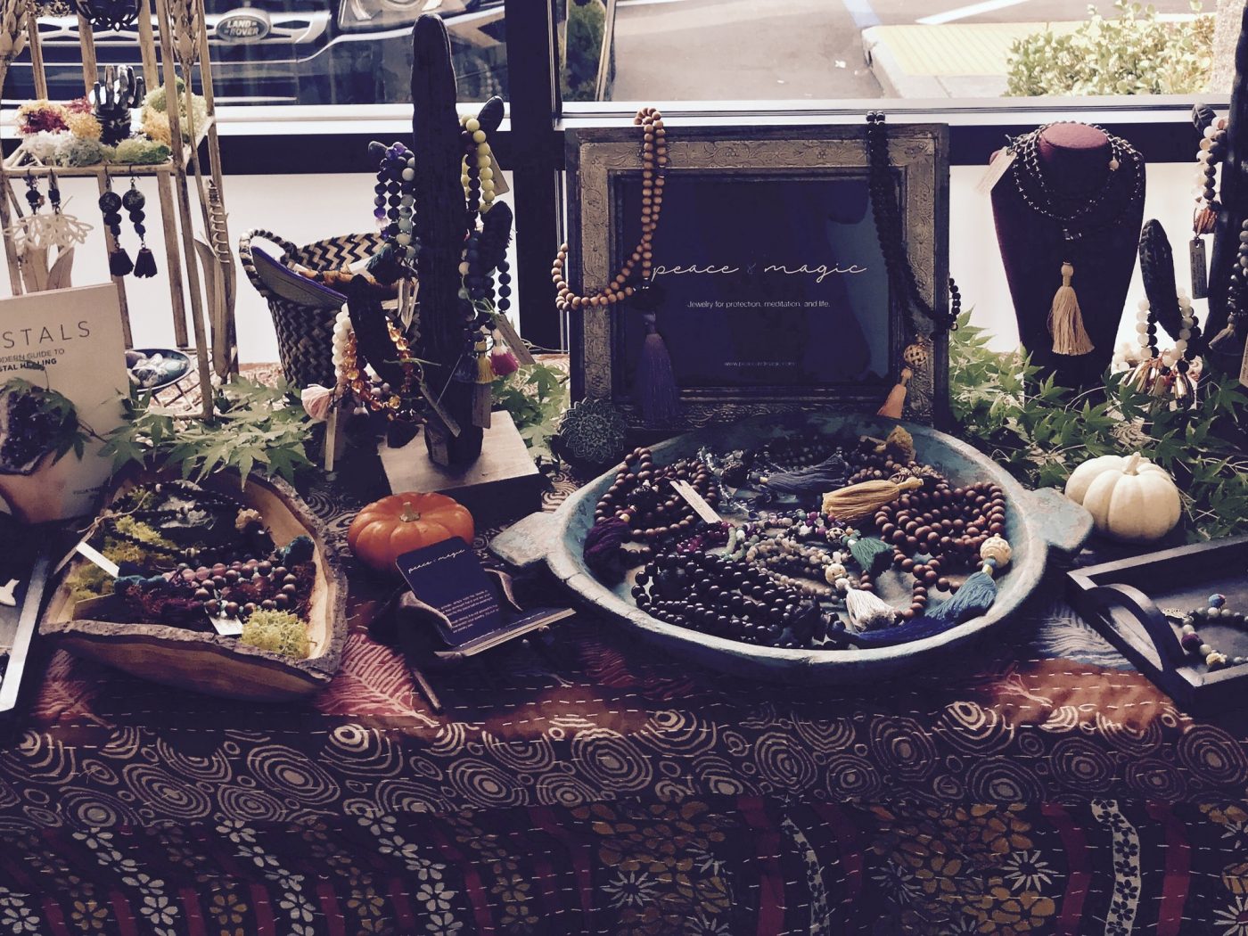 A moody pop up table with malas, crystals and small pumpkins.