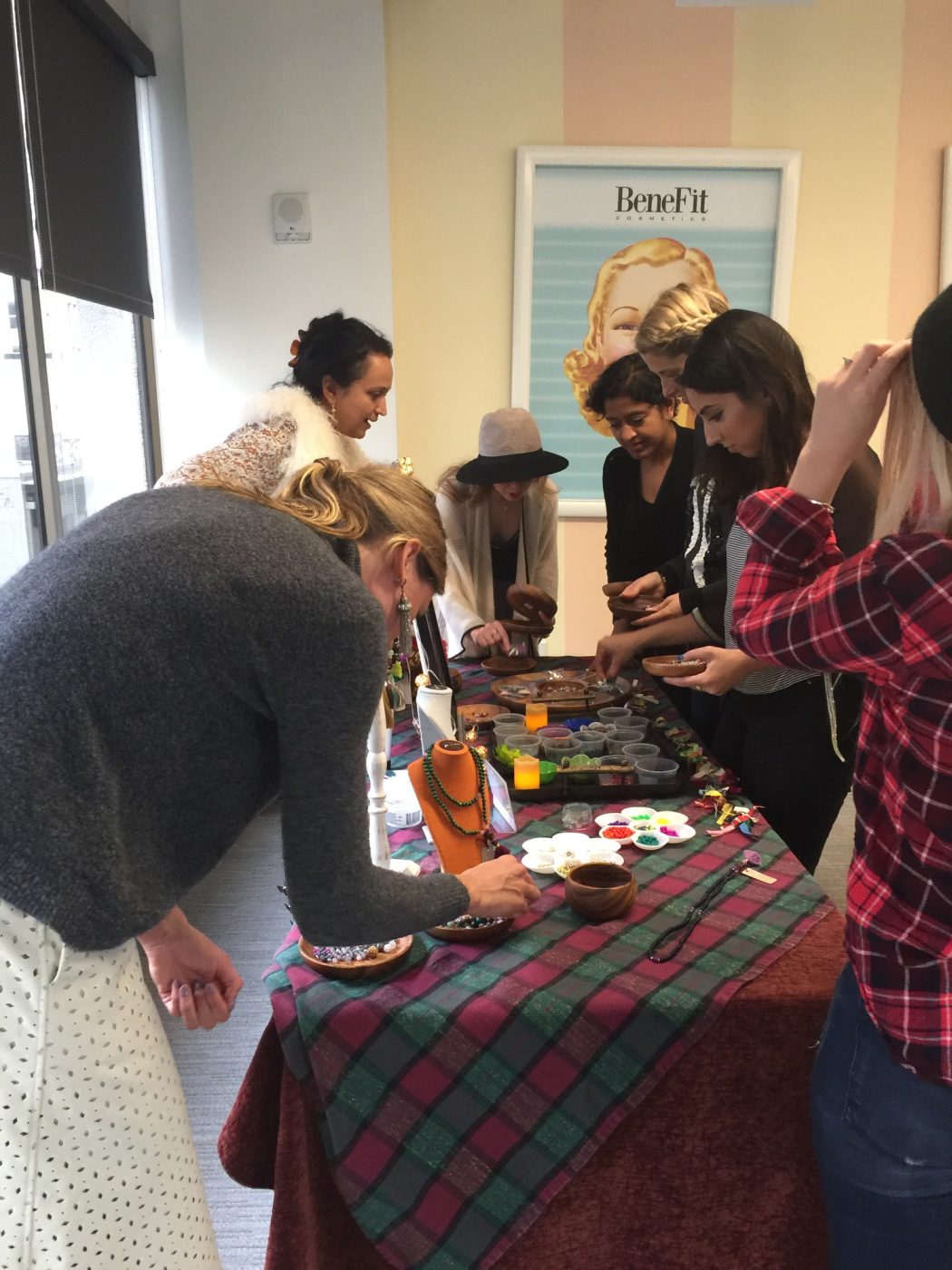 Women gathered around a table making jewelry at a workshop.
